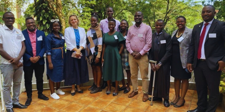 Amb. Katie Airey, the Ambassador of the British High Commission to Uganda, dressed in a white coat and dark blue skirt, posing with the OYW ambassadors following a visit to her residence to reflect on the OYW summit experience and explore avenues for continued collaboration.